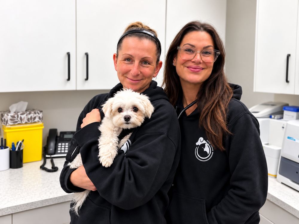 Two team members holding a fluffy white dog